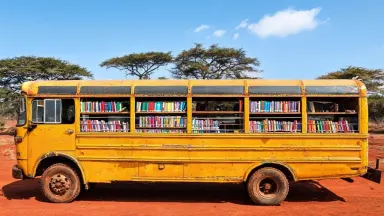 Push in slowly and steadily toward the open bus window, the colorful book spines coming progressively into sharper focus, dus