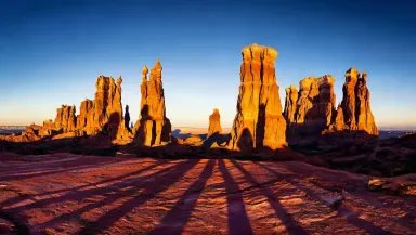Tilt the camera slowly upward from the purple shadow line on the mesa floor past the banded hoodoo columns to the amber-lit s