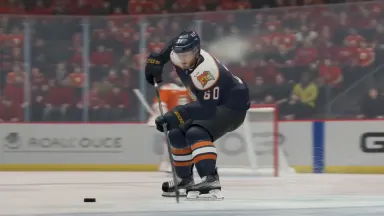 Ice hockey defenseman at full extension blocking a hard slap shot, puck a dark frozen disc inches from his paddle blade, ice 