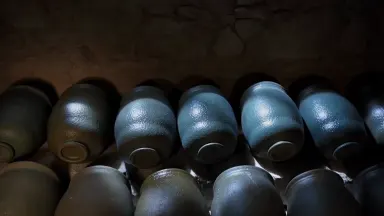 Overhead top-down view of rows of salt-glazed stoneware storage crocks lining the stone shelf of a historic farmhouse cellar,