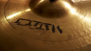 The hammered surface of a bronze cymbal fills the frame completely, concentric tool marks radiating outward from the raised b