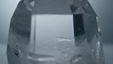 Surface of a large quartz crystal point seen straight down the c-axis, internal inclusion clouds drifting in pale grey depth 