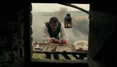 Napoleonic-era battlefield surgeon working at a wooden field table outside a stone farmhouse, period instruments laid in a ro