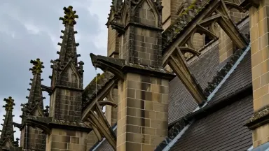 Gothic flying buttresses of a cathedral apse seen from roof level with lead valleys and gargoyle drainage spouts in close det