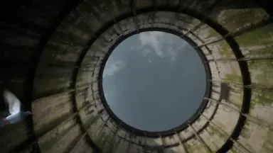 Interior of an abandoned industrial hyperbolic cooling tower viewed from floor level looking upward, mossy concrete ribs spir