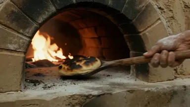 Ancient Roman bread baker pulling charred loaves from a domed clay oven in a Pompeii street bakery, slow dolly drawing back f