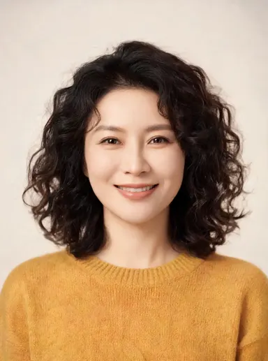Studio portrait of a friendly woman in her 30s with curly dark hair, warm smile, mustard sweater, soft neutral backdrop, faci